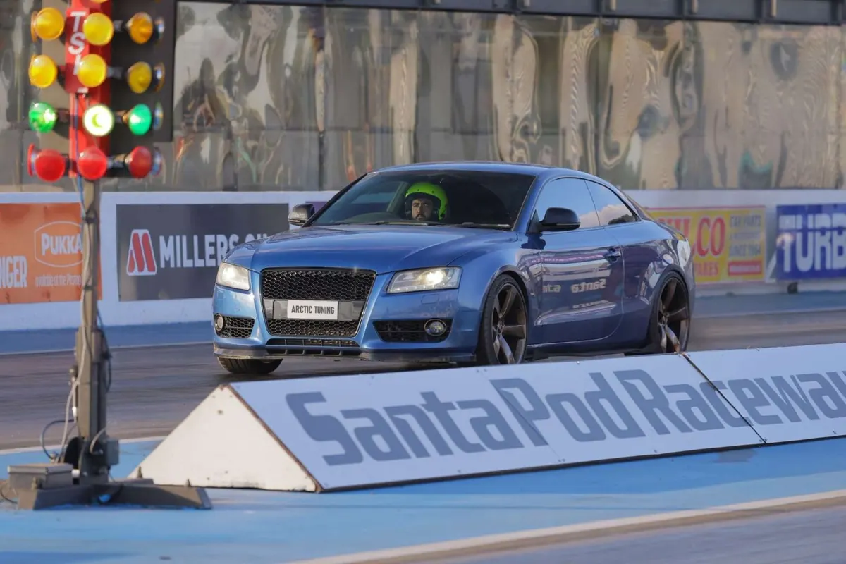 A blue Audi A5 on the start line at Santa Pod Raceway, the start lights on green