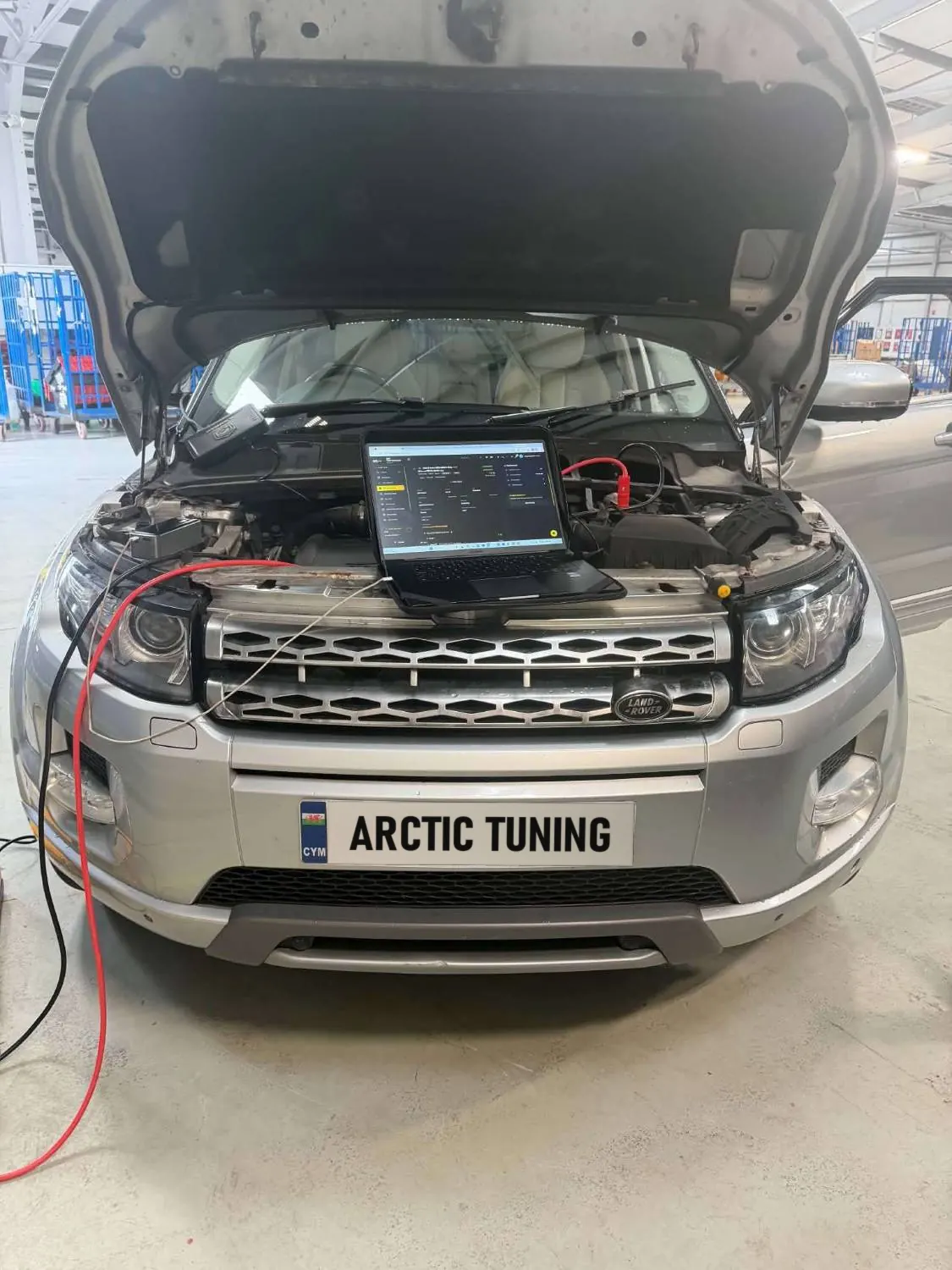 A silver Range Rover Evoque with its bonnet up and a laptop on the slam panel