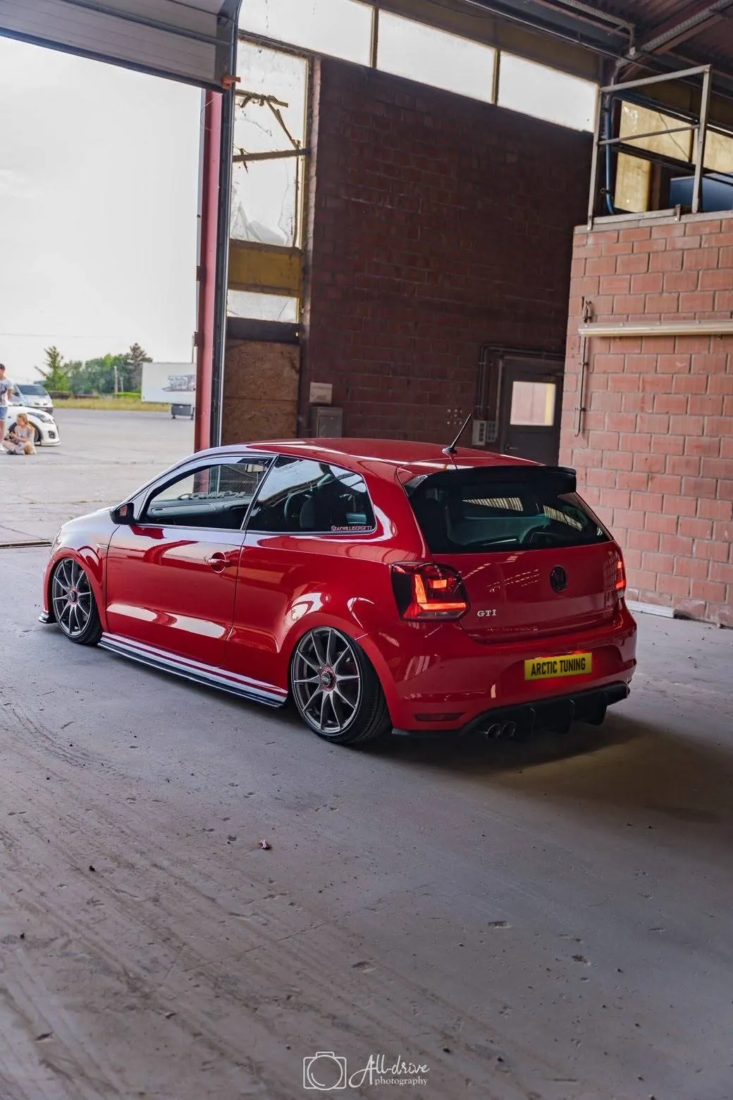 The back of a lowered red Polo GTI with its tail lights on